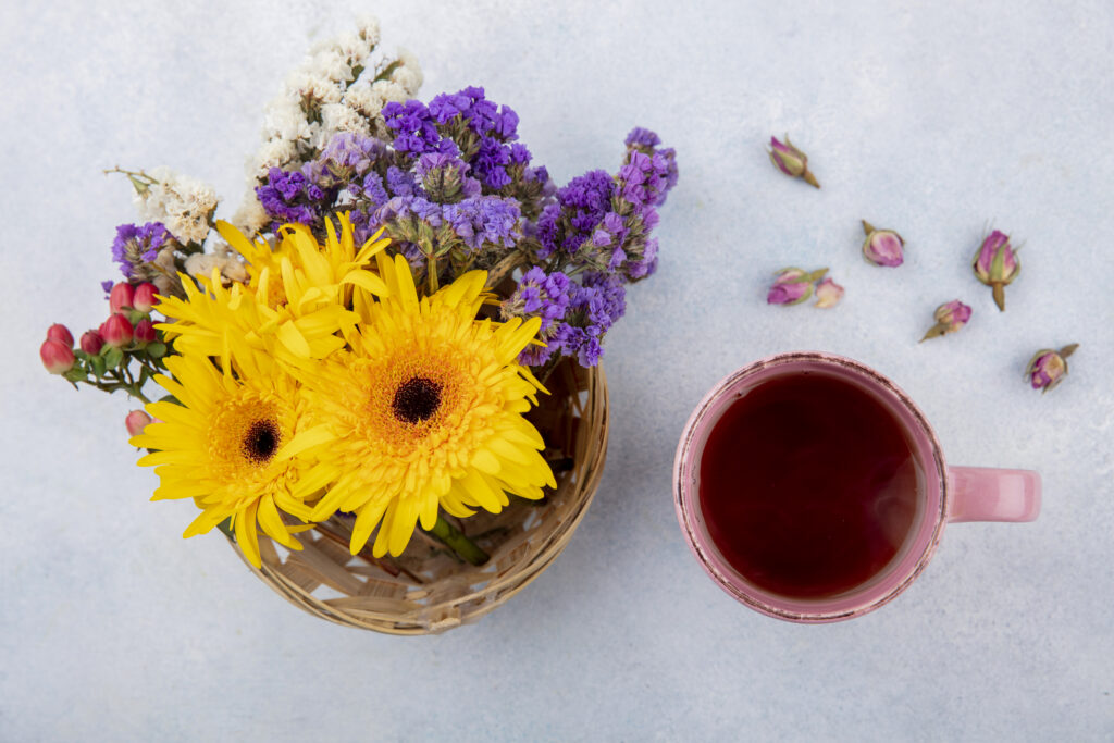 top view of cup of tea and flowers in basket and on white background Masale Caya